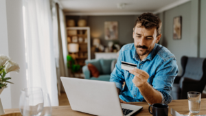 Young man using his credit card on the laptop