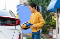 Asian person hooking up an electric plug-in to their electric car