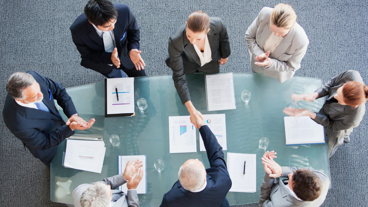Business people shaking hands across conference room table