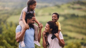 parents carrying their small kids on shoulders in nature