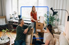 Millennial with moving box talking to parents in their house