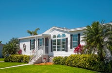 Luxury caravan, mobile home, landscaped with front lawn, palm trees, clear sky