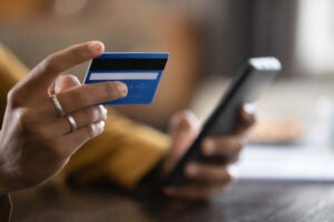 Close up cropped view of someone shopping on mobile phone with a credit card