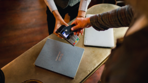 A directly-above shot of a man paying with his credit card on a credit card reader.