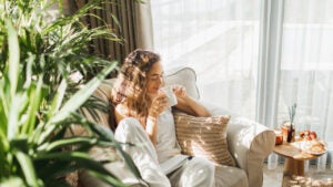 Woman at home reading book and drinking coffee