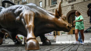 Tourists visit the Wall Street bull statue in the Financial District