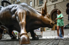 Tourists visit the Wall Street bull statue in the Financial District