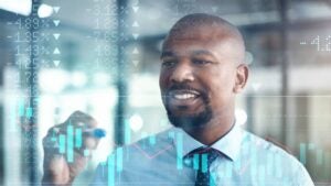 businessman working in the office superimposed over a graph showing the ups and downs of the stock market