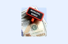 A sign reading "municipal bonds" sits on top of a hundred- dollar bill.