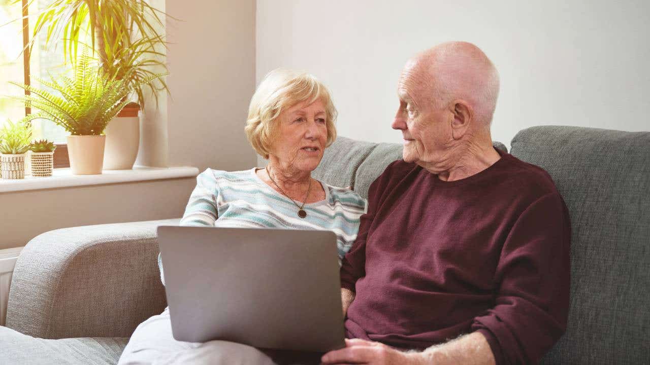 senior couple using a laptop on the sofa at home