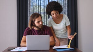 couple by table working from home using laptop and checking documents