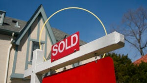 upward view of home with red sold sign outside