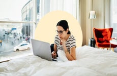 design image depicting a woman laying on her bed on her laptop