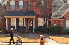 A woman pushes her granddaughter in a stroller in front of her suburban house near Dallas, Texas