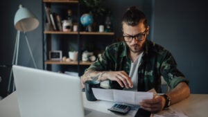 Young man calculates finances at a table