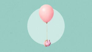 A piggy bank floating away attached to a large balloon