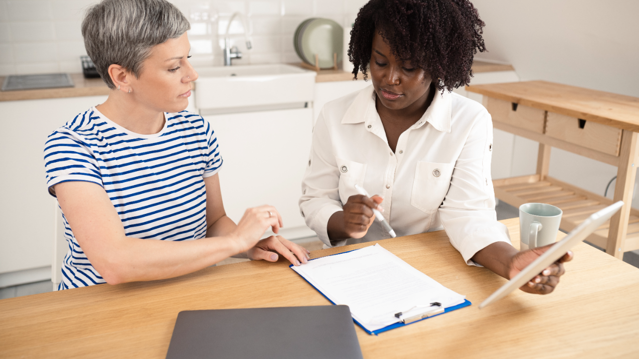 Two women look at a clipboard and tablet