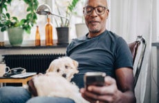 Smiling man using smart phone while sitting with dog