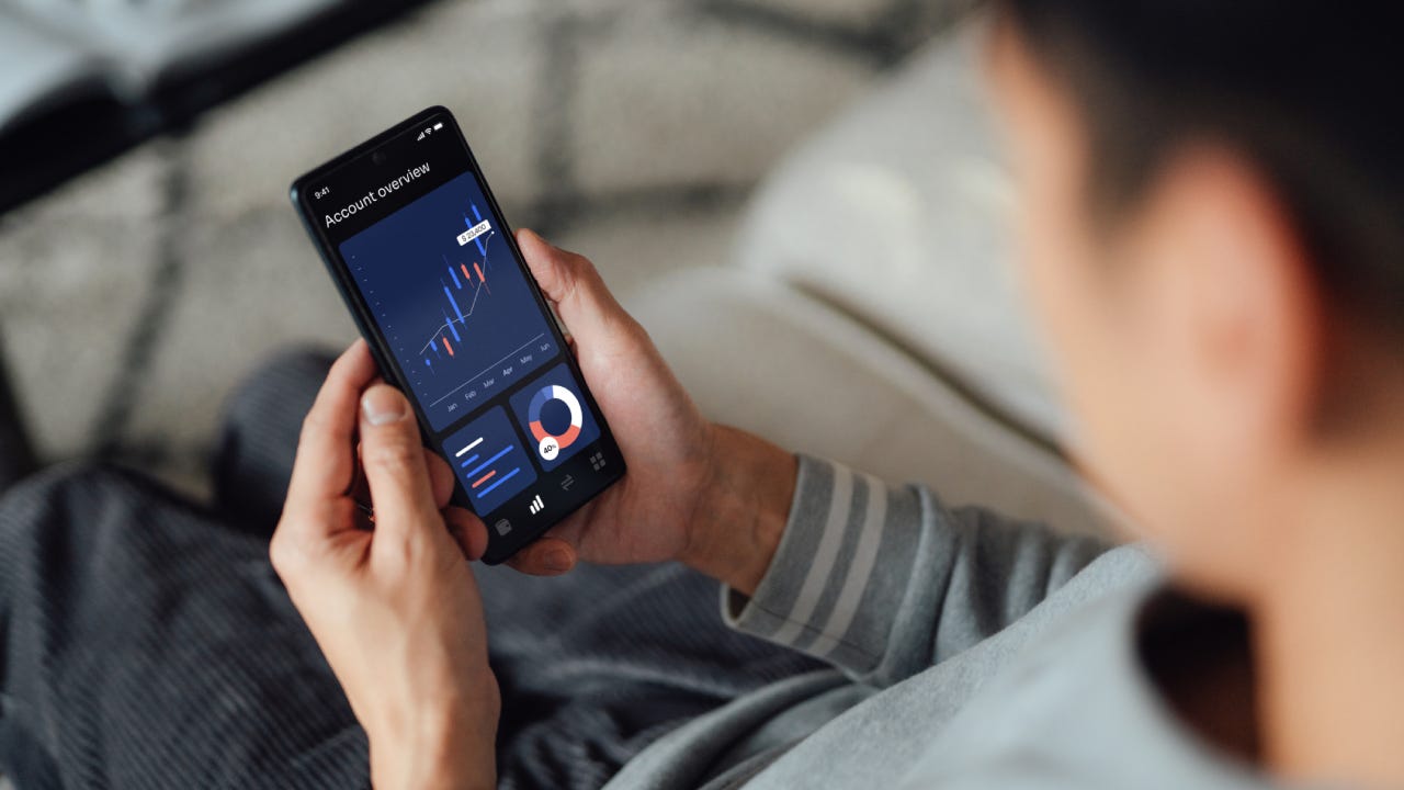 Over the shoulder view of young man checking financial data with mobile banking app