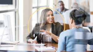 Two people talking in front of a computer