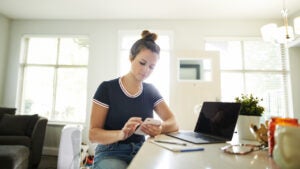 young woman using a mobile phone while working at home