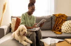 Woman working on a tablet with a dog sitting next to her