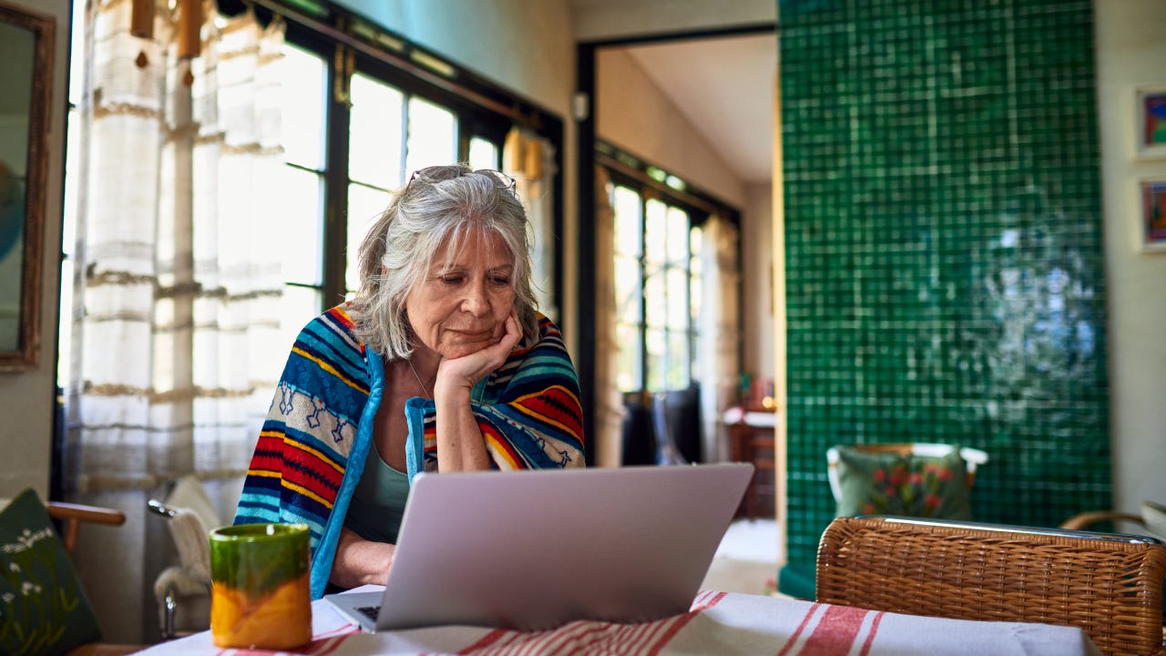 Grey haired woman working from home using laptop