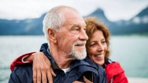 Couple standing on a dock with an out-of-focus body of water behind them.