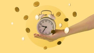 A picture of a pale hand holding an alarm clock with coins falling around it on a yellow background.