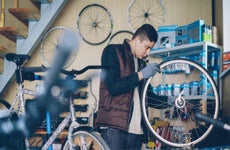 Self-employed mechanic is repairing bicycle wheel with wrenches