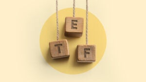 Block letters that spell out "ETF" hang from string in front of a yellow background.