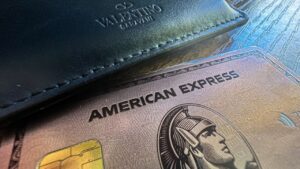 American Express card laying on table next to a wallet