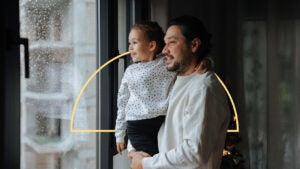 A parent and child watch falling rain.