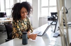 Woman with a credit card talking into a smart assistance device to do a online payment