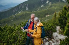 Portrait of senior man and woman reading map during hike in autumn mountains