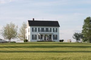 white farmhouse with black shutters and green lawn