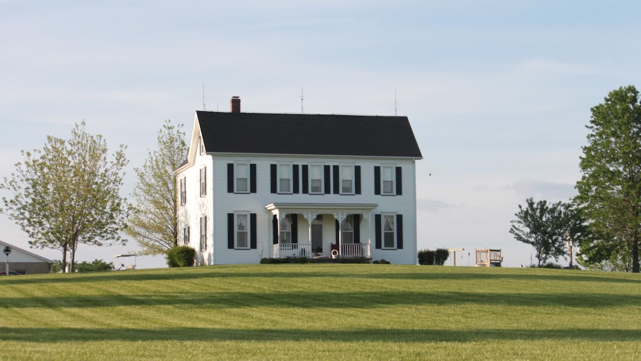 white farmhouse with black shutters and green lawn