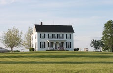 white farmhouse with black shutters and green lawn