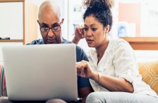 Couple looking at laptop while sitting on sofa at home