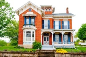 historic red brick home with elaborate white trim and blue shutters