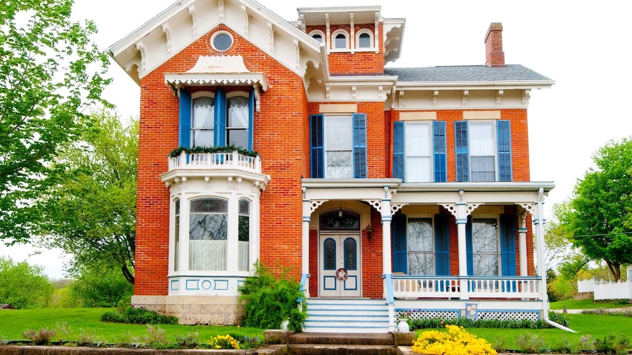 historic red brick home with elaborate white trim and blue shutters