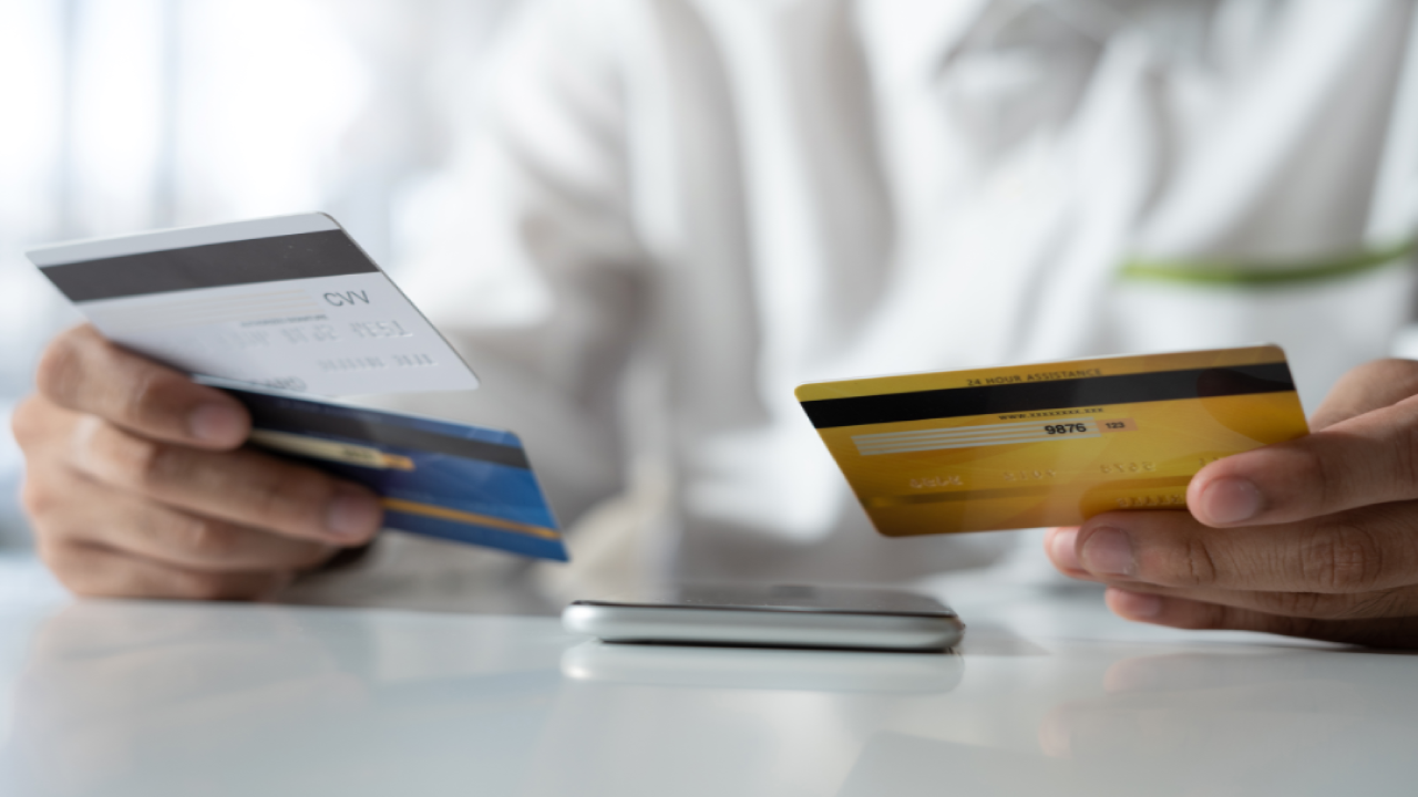 Person holding three credit cards over their phone.