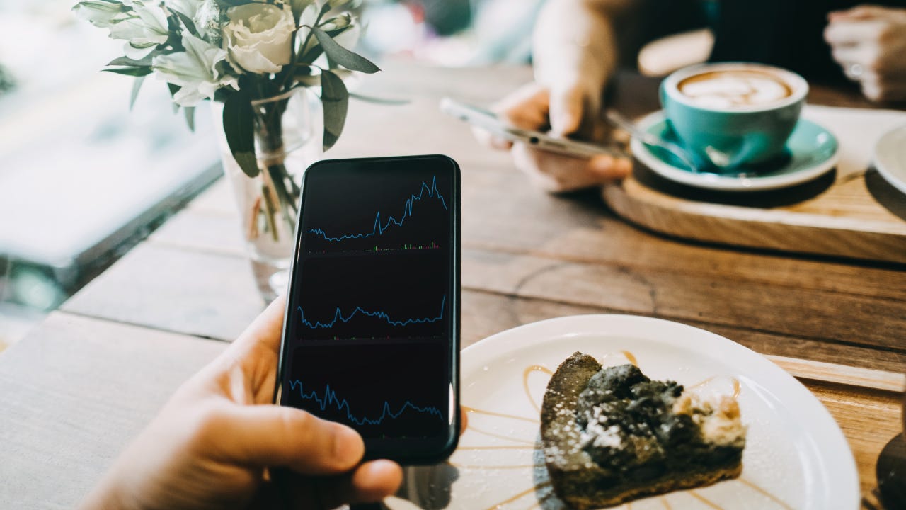 Busy people working and checking financial trading data on smartphone in cafe