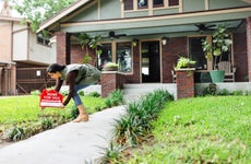 realtor placing red for sale sign outside craftsman style house