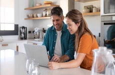 Two people in a kitchen looking at a laptop.