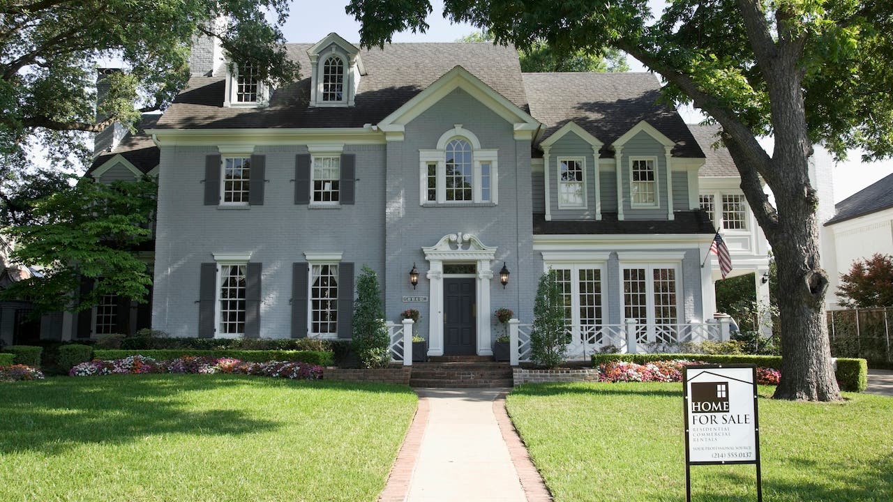 large gray and white house exterior with for sale sign in dallas tx