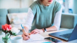 Young woman managing finances using laptop and smartphone.