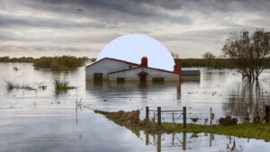 A partially-submerged house against a gray sky after a major storm and flooding