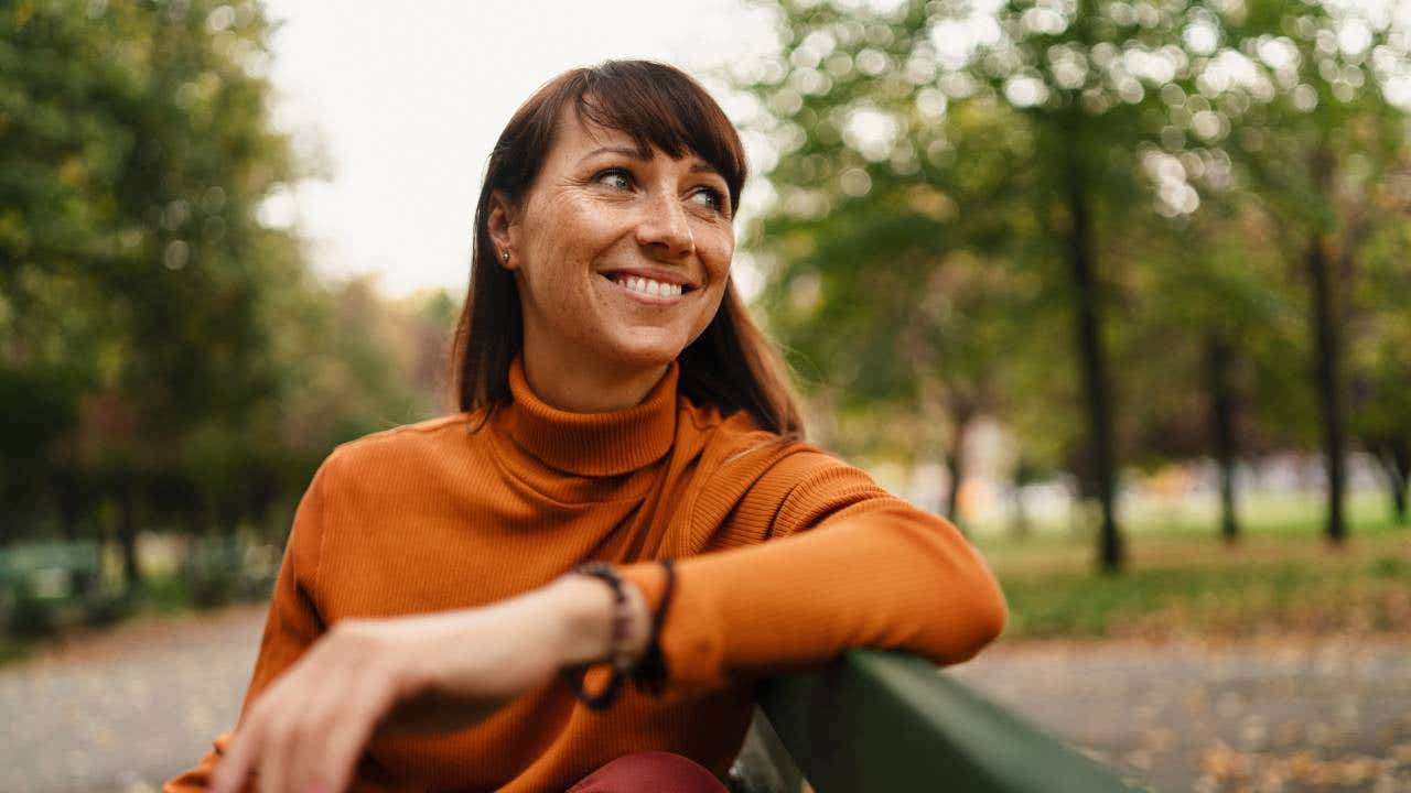 Person sitting on a park bench and smiling.