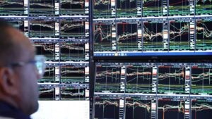 Person looking at multiple trading screens displaying charts.